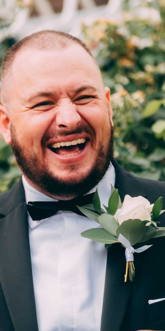 Groomsman laughing in a suit at a wedding at Moor Hall in Sutton Coldfield